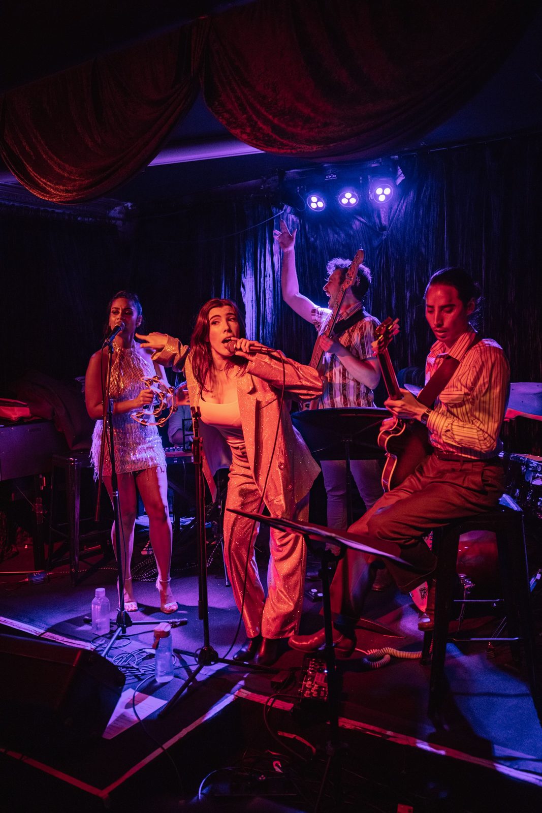 Jess Fairlie fronting her live band under red light