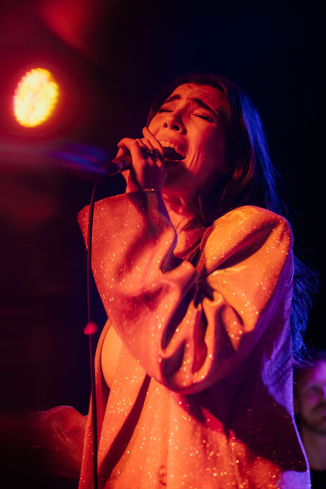 Jess Fairlie singing live under red stage lights