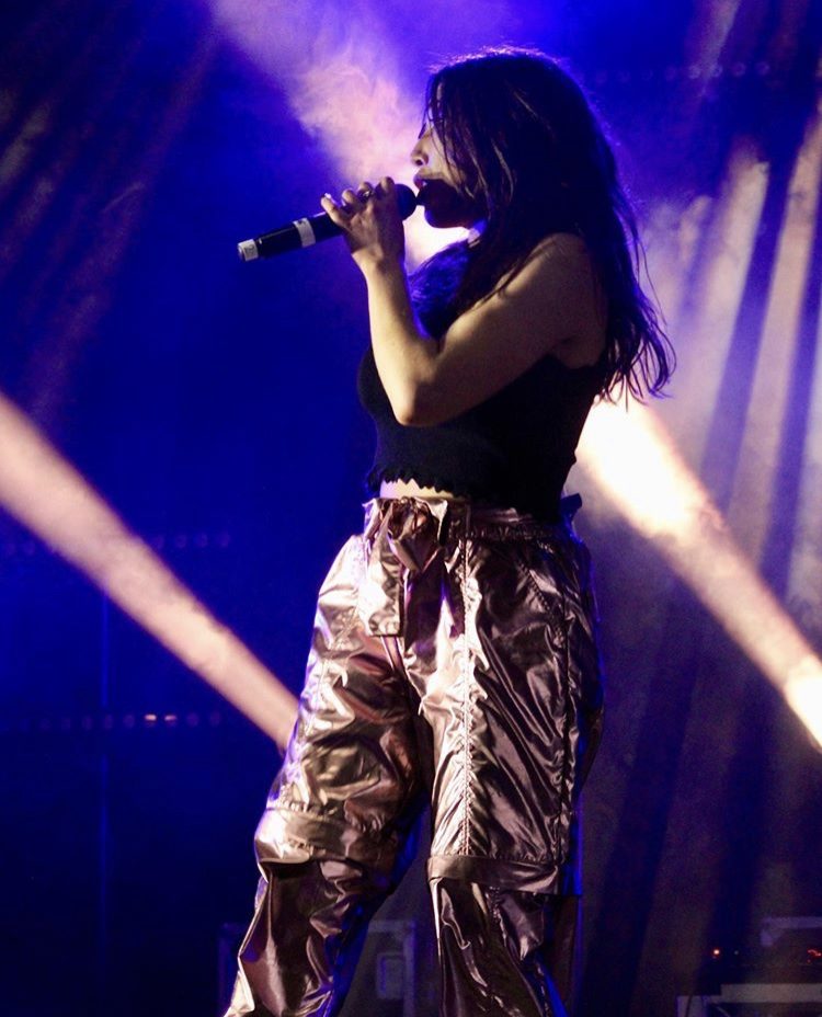 Jess Fairlie singing under blue stage lights